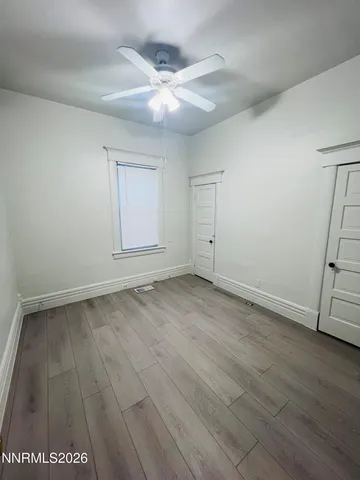 an empty room with wooden floor and fan
