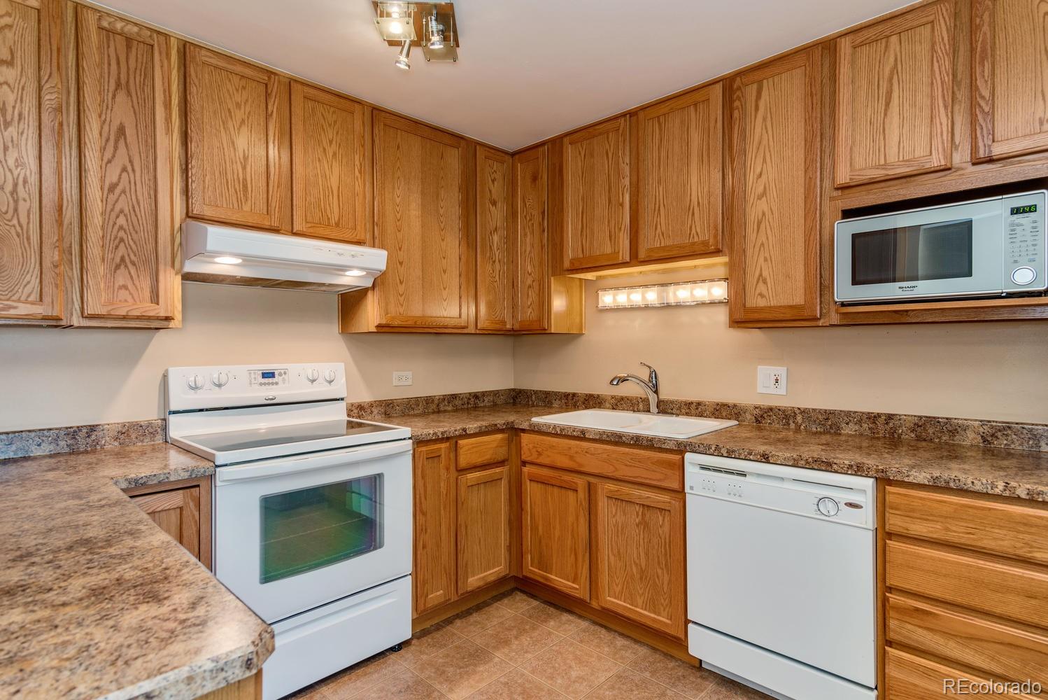 9155 Center Avenue, Unit 9B Denver, CO 80247 - Photo 1 of 35 a kitchen with granite countertop wood cabinets stainless steel appliances and a sink