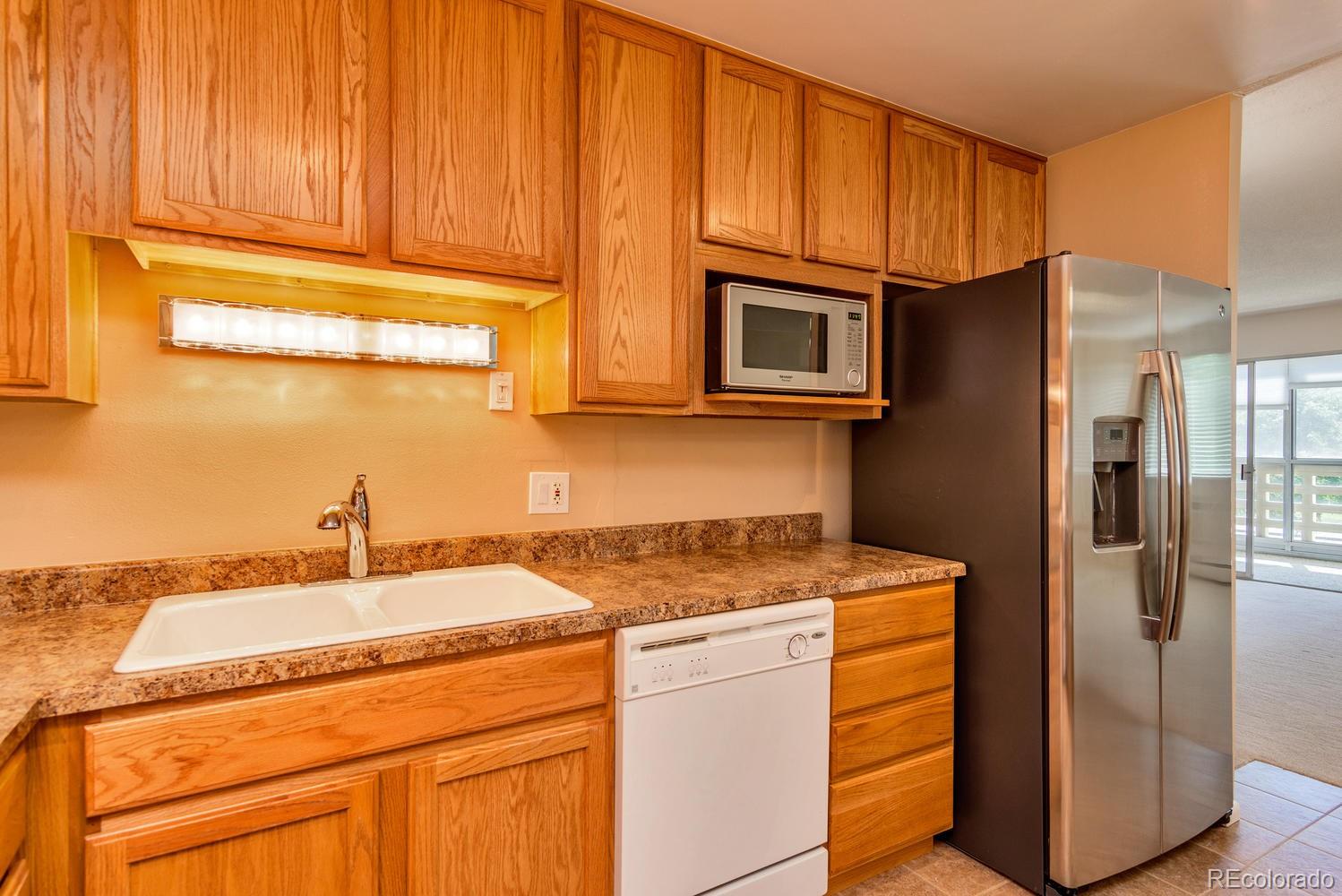 9155 Center Avenue, Unit 9B Denver, CO 80247 - Photo 3 of 35 a kitchen with stainless steel appliances granite countertop a refrigerator sink and cabinets