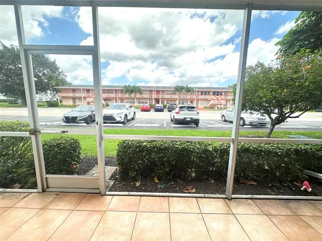 a view of a white house with a big yard and potted plants and large trees