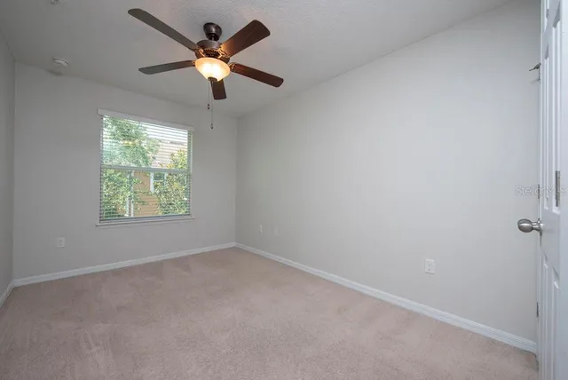 an empty room with ceiling fan and window