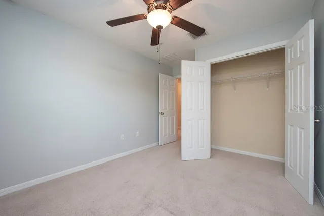 an empty room with closet and a chandelier fan