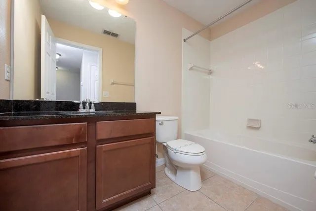 a bathroom with a granite countertop sink a toilet a mirror and shower