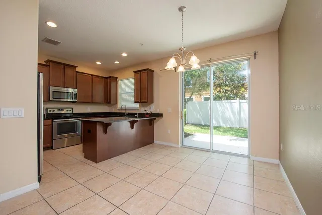 a kitchen with stainless steel appliances granite countertop a refrigerator a sink a stove top oven and a large window