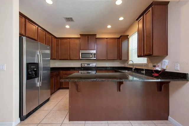 a kitchen with kitchen island granite countertop a sink window and refrigerator