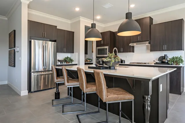 a kitchen with kitchen island granite countertop a sink chairs and refrigerator