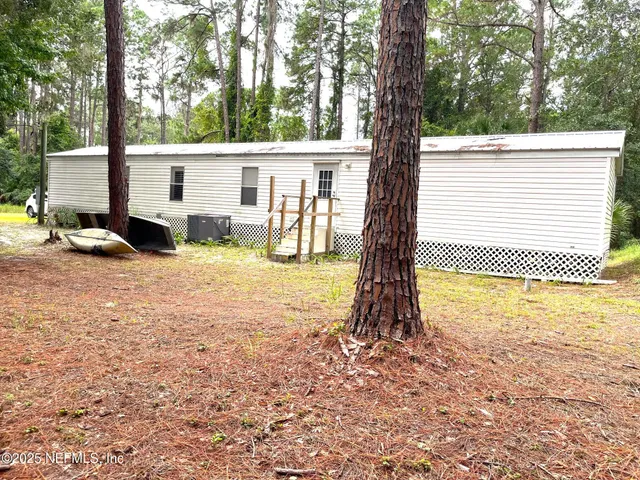 a view of backyard with large trees and wooden fence