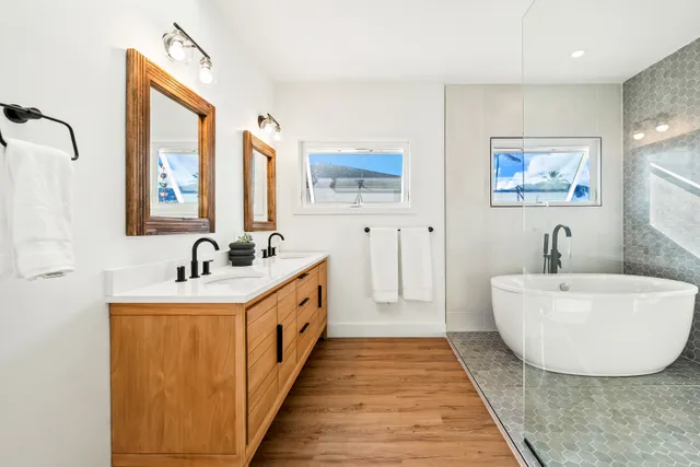 a bathroom with a double vanity sink mirror and bathtub