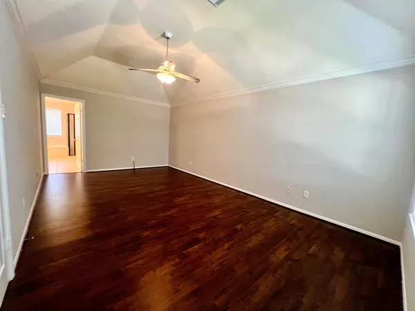 an empty room with wooden floor and fan