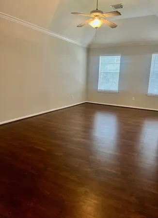 an empty room with wooden floor fan and windows