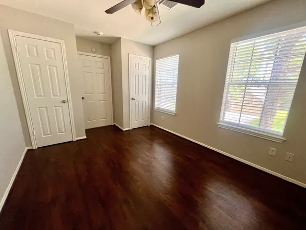 a view of an empty room with a window and wooden floor