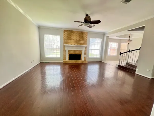 a view of an empty room with wooden floor fireplace and a window