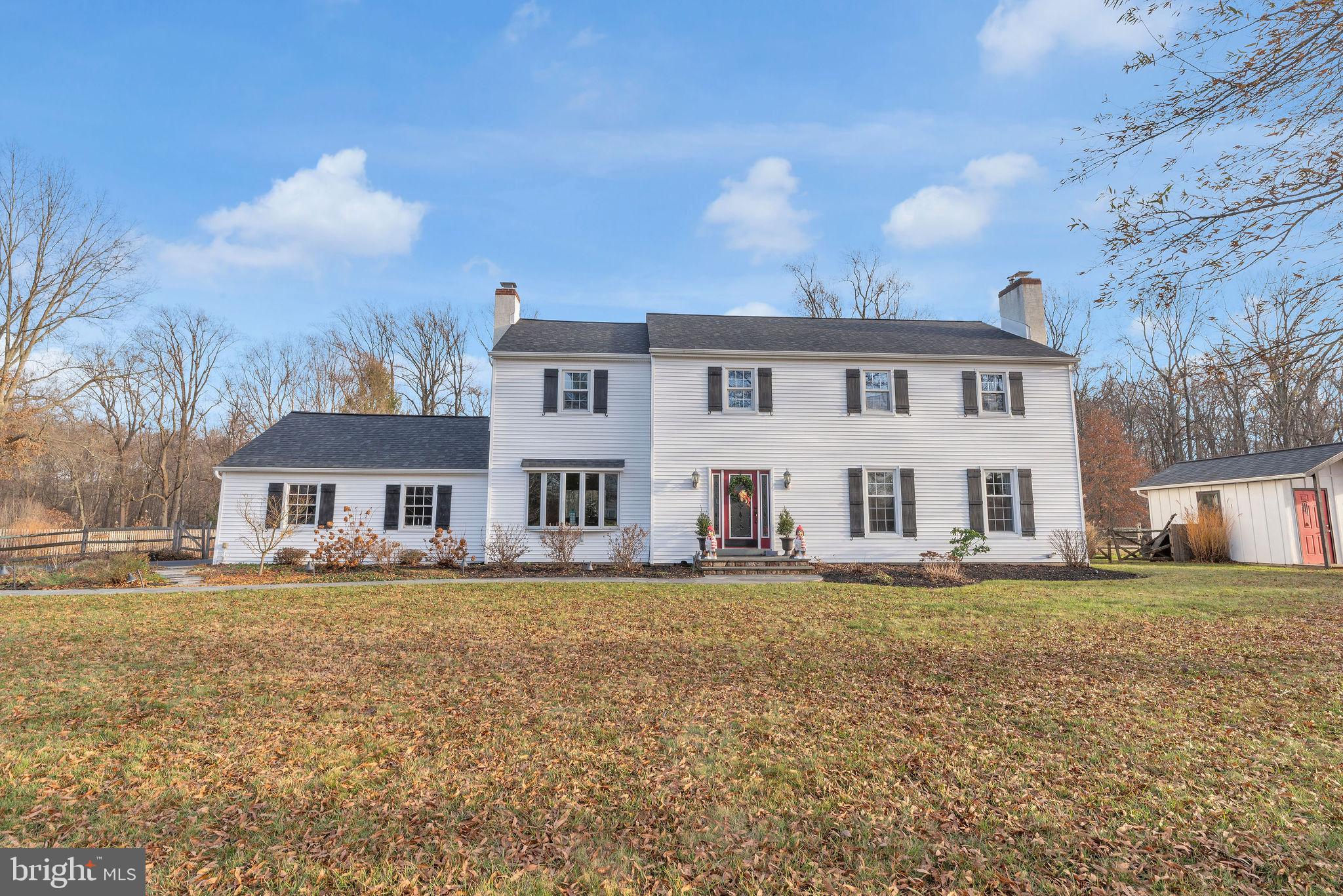 a view of a white house with a big yard and large trees