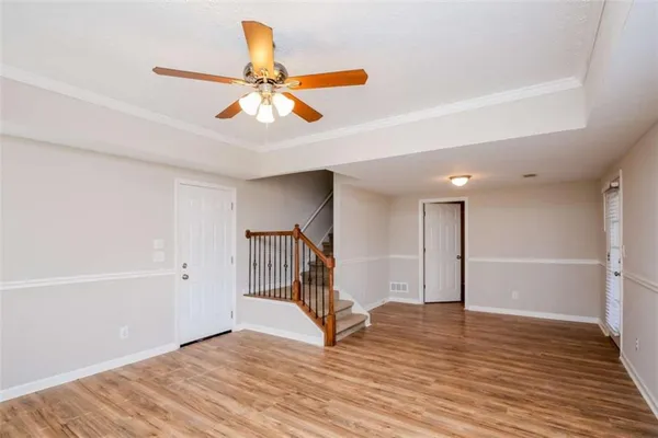 a view of an empty room with wooden floor and a ceiling fan