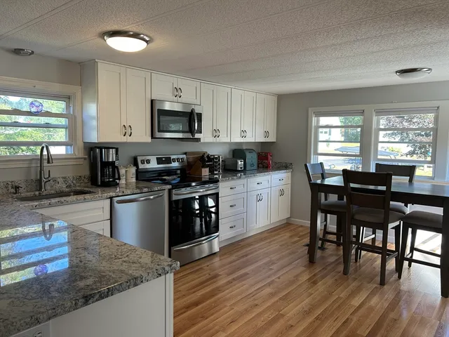 a kitchen with stainless steel appliances granite countertop a stove a sink dishwasher a microwave oven with a dining table and chairs