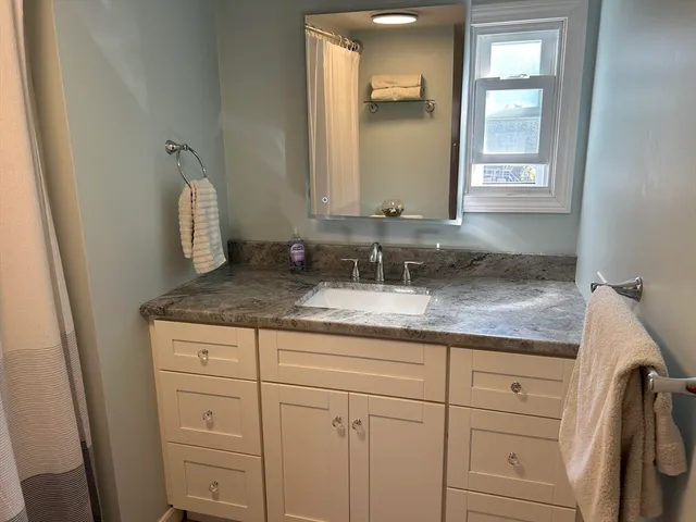 a bathroom with a granite countertop sink and a mirror
