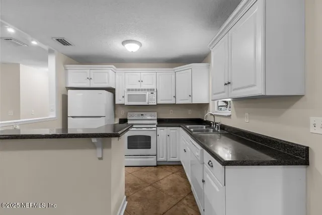 a kitchen with granite countertop a sink a stove and cabinets