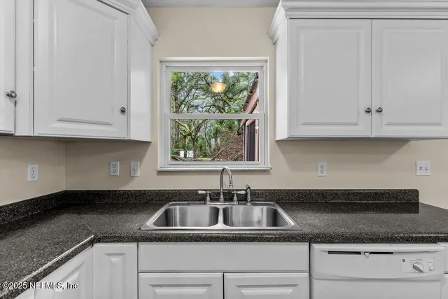 a kitchen with granite countertop white cabinets and a sink
