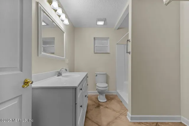 a bathroom with a granite countertop sink and a toilet