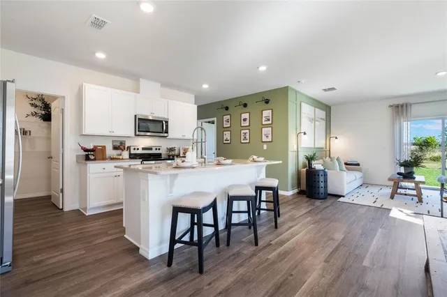a kitchen with microwave a refrigerator and chairs