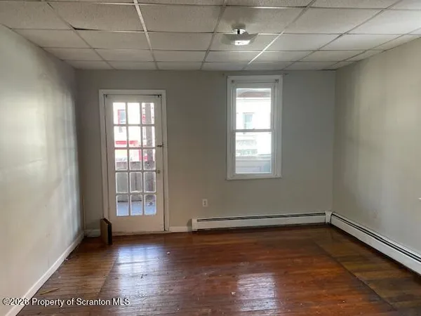 an empty room with wooden floor and windows