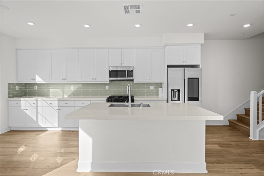 1713 Jade Road Rancho Mission Viejo, CA 92694 - Photo 14 of 53 a large kitchen with stainless steel appliances granite countertop a stove a sink a refrigerator and white cabinets with wooden floor