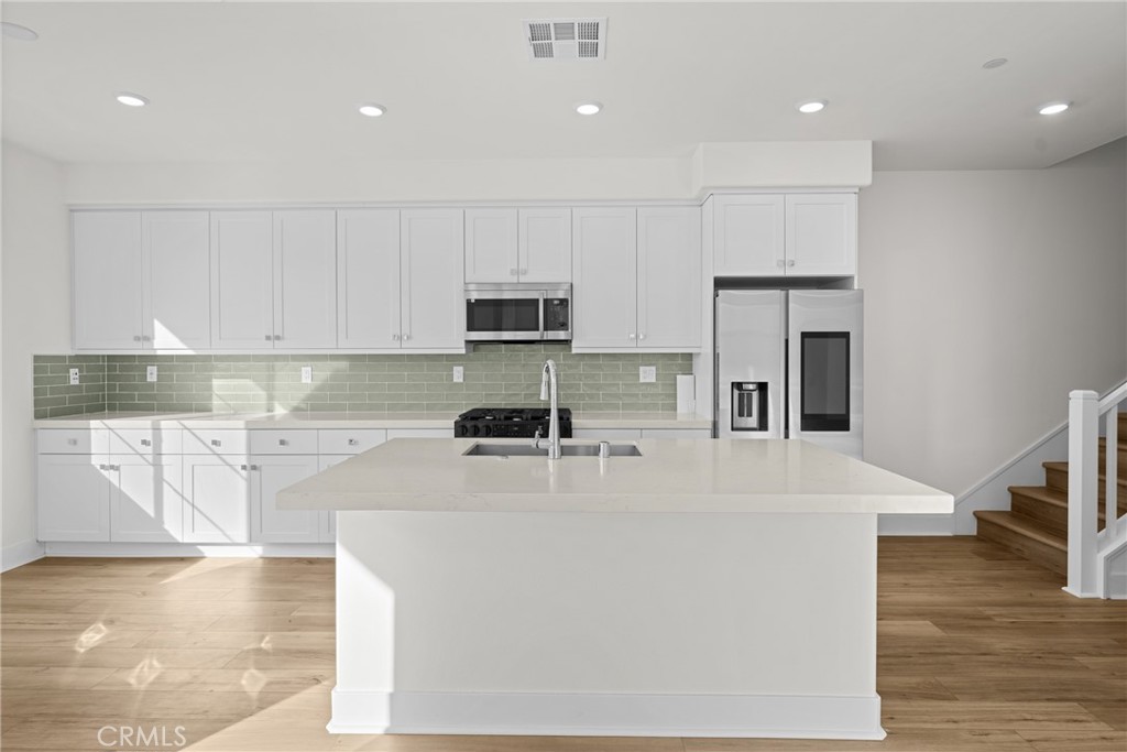 1713 Jade Road Rancho Mission Viejo, CA 92694 - Photo 15 of 53 a kitchen with kitchen island a stove a sink a refrigerator and white cabinets with wooden floor