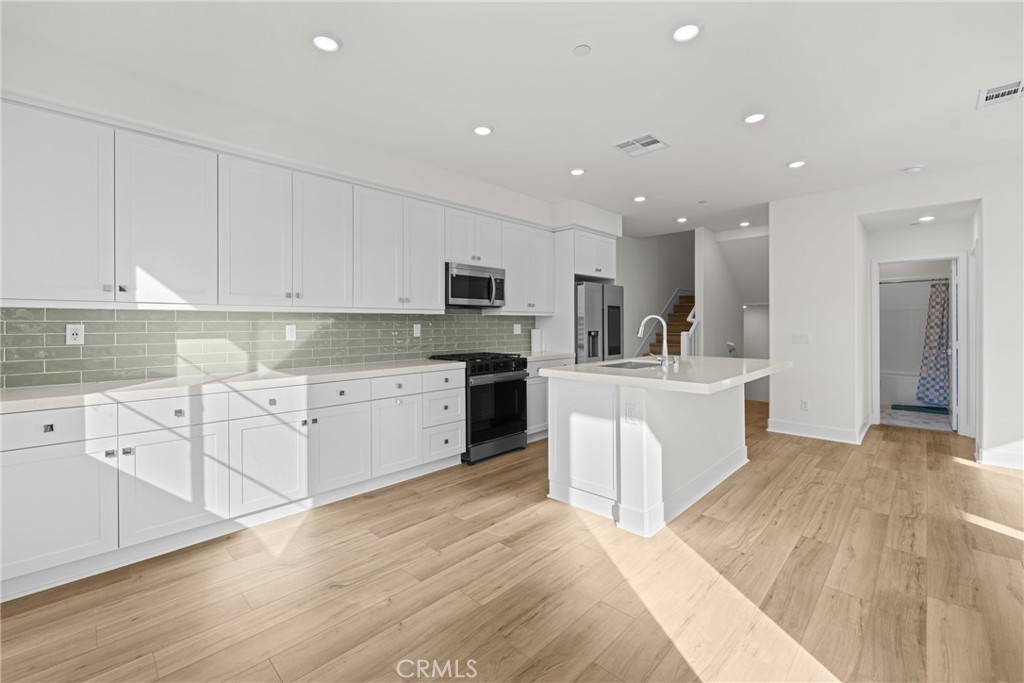 1713 Jade Road Rancho Mission Viejo, CA 92694 - Photo 22 of 53 a large white kitchen with kitchen island a sink a center island stainless steel appliances and a cabinets
