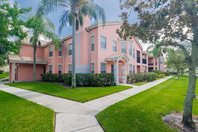 a view of a building next to a big yard and large trees