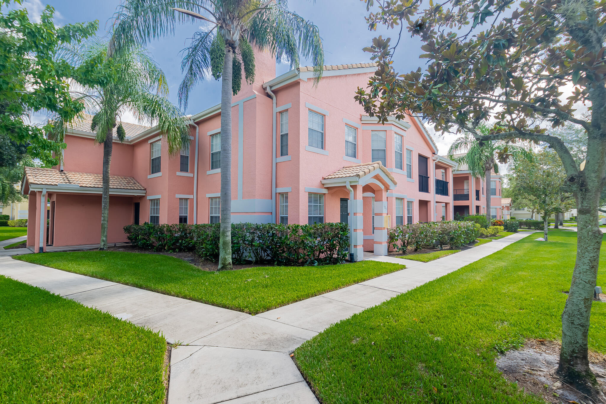 168 Southwest Peacock Boulevard, Unit 35103 Port St. Lucie, FL 34986 - Photo 1 of 43 a view of a building next to a big yard and large trees