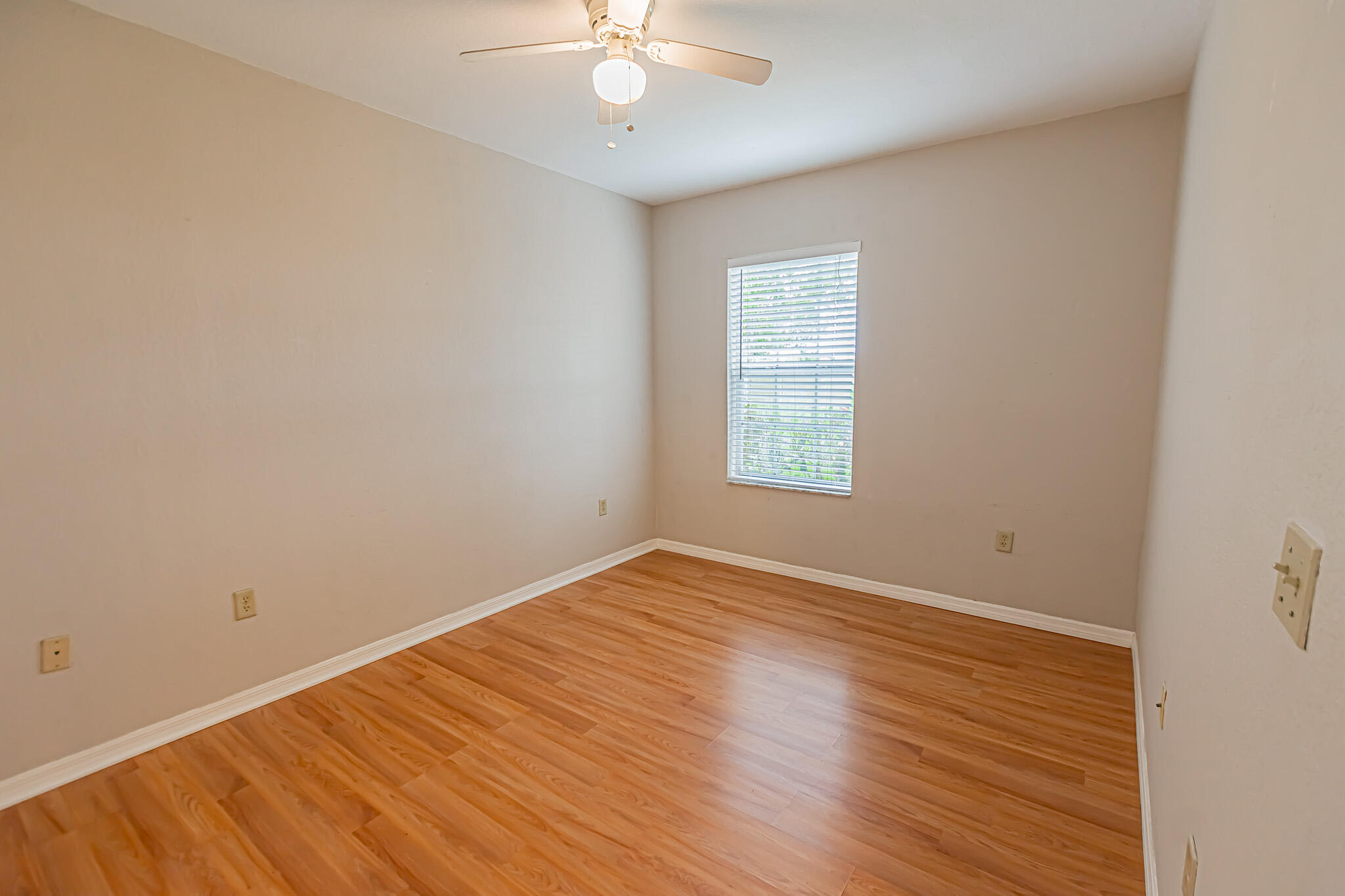 168 Southwest Peacock Boulevard, Unit 35103 Port St. Lucie, FL 34986 - Photo 16 of 43 an empty room with wooden floor fan and windows