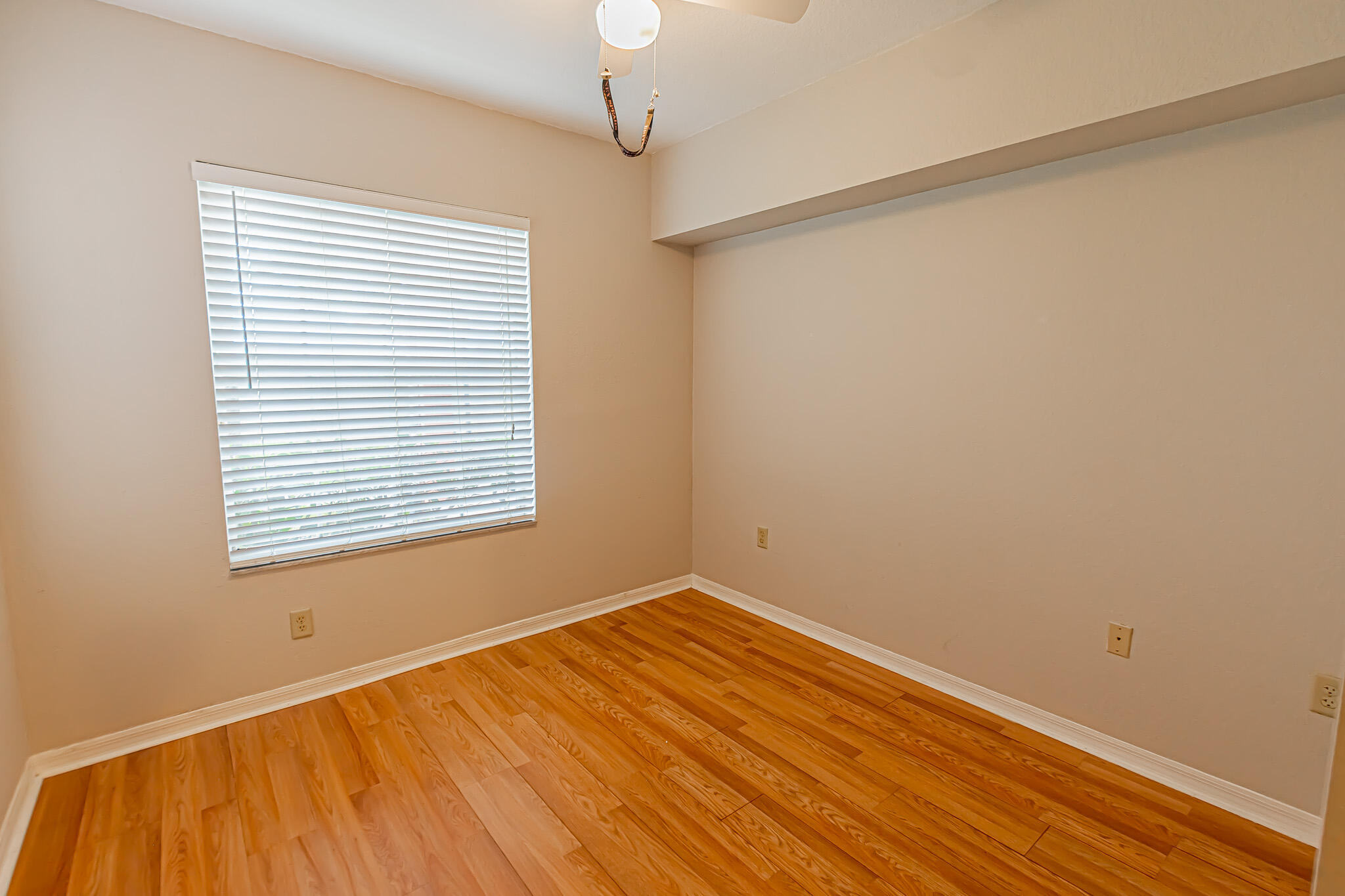 168 Southwest Peacock Boulevard, Unit 35103 Port St. Lucie, FL 34986 - Photo 19 of 43 a view of an empty room with a window and wooden floor