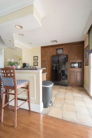 a kitchen with stainless steel appliances kitchen island granite countertop a table chairs and a refrigerator