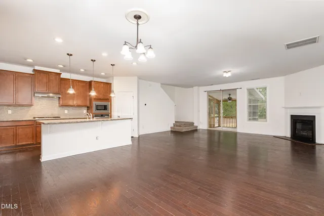 a large kitchen with stainless steel appliances a large counter top a stove and a wooden floors