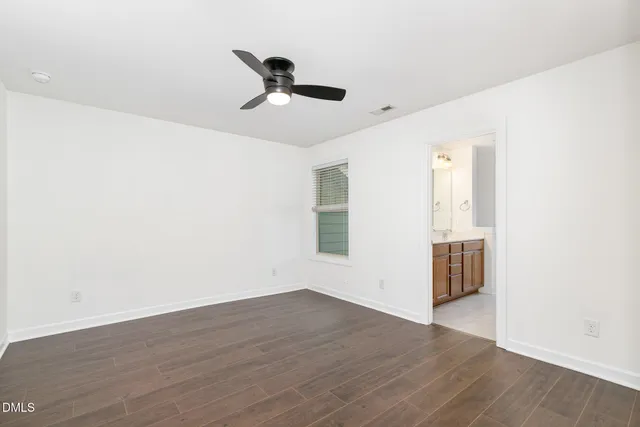 an empty room with wooden floor cabinet and windows