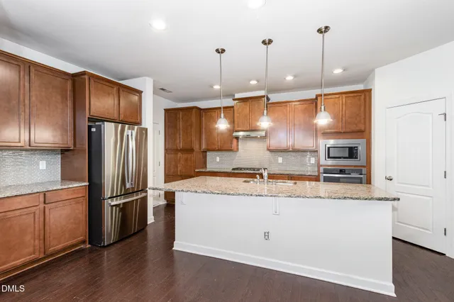 a kitchen with stainless steel appliances granite countertop a refrigerator a sink dishwasher a stove and white cabinets with wooden floor