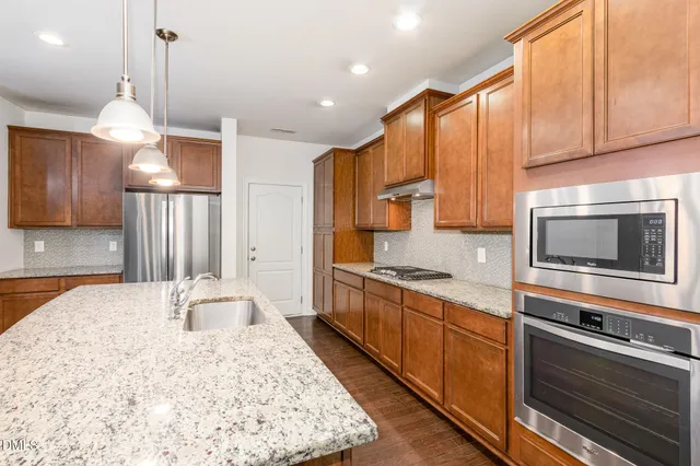 a large kitchen with stainless steel appliances granite countertop a stove a sink and a microwave