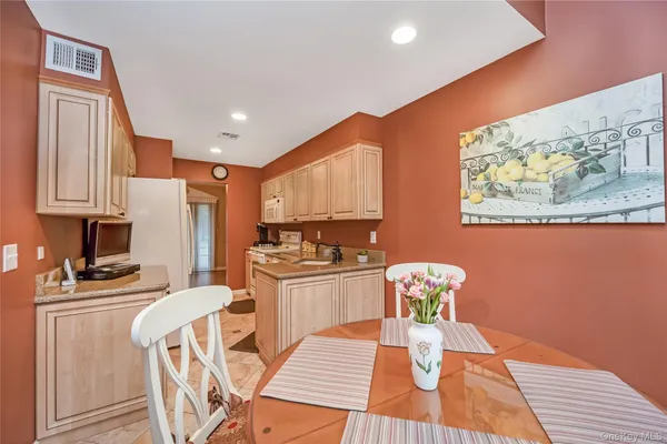 a kitchen with stainless steel appliances granite countertop a stove top oven a dining table and chairs with wooden floor