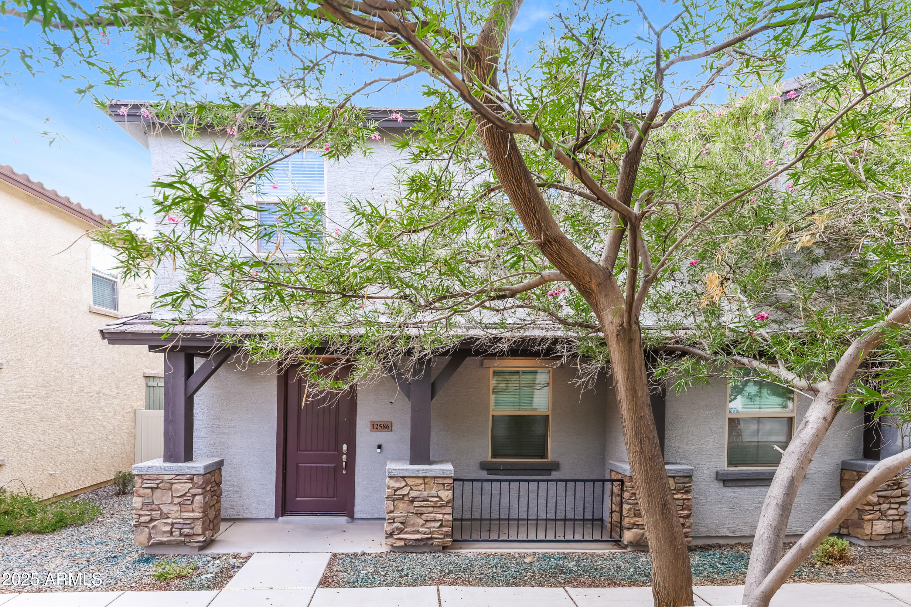 a front view of a house with a tree