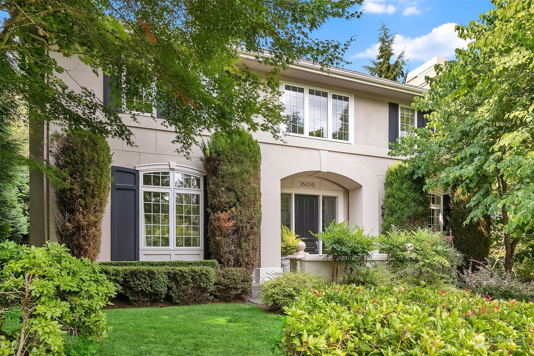 a front view of a house with plants and trees