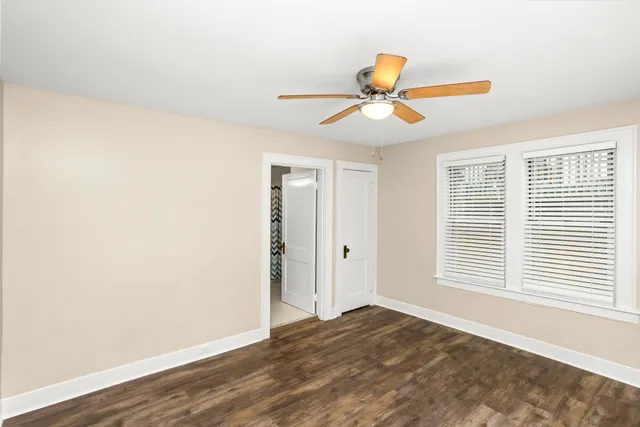 a view of empty room with wooden floor and fan