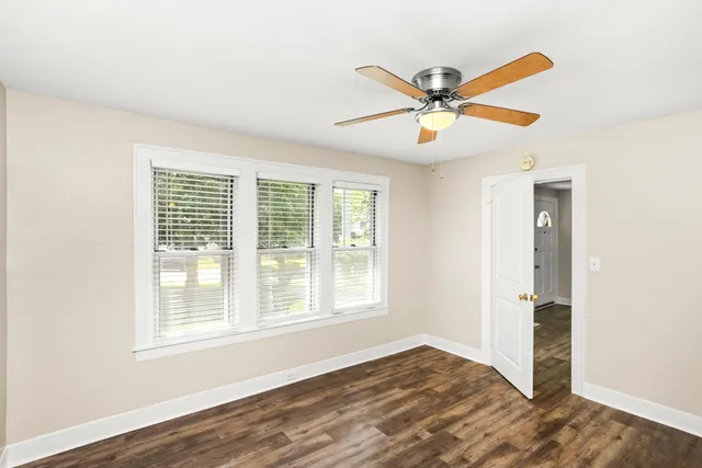 a view of an empty room with window and a ceiling fan