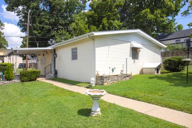 a backyard of a house with potted plants and large tree