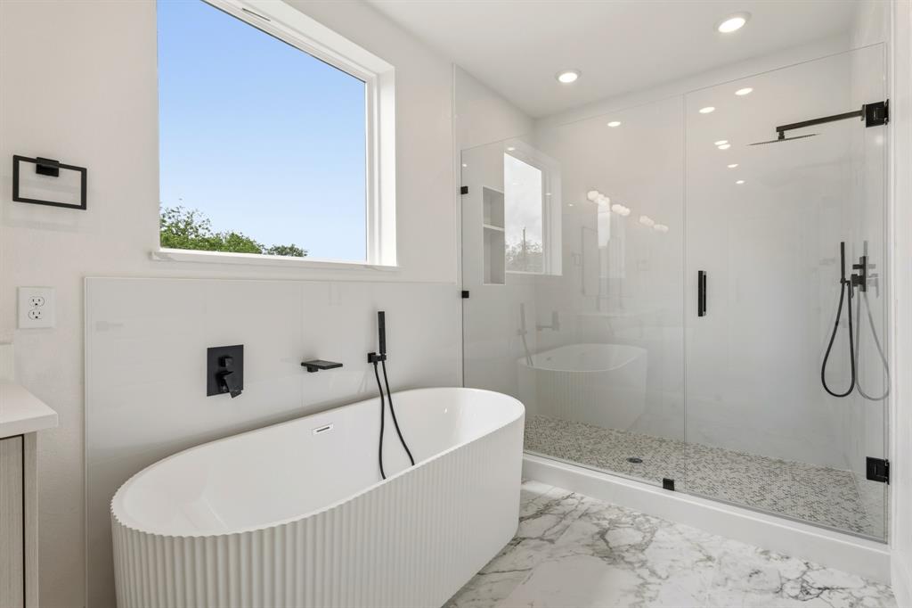 415 North Patton Avenue Dallas, TX 75203 - Photo 10 of 20 The bathroom features a modern freestanding tub, a spacious glass-enclosed shower with a pebble floor, and large format marble-look floor tiles