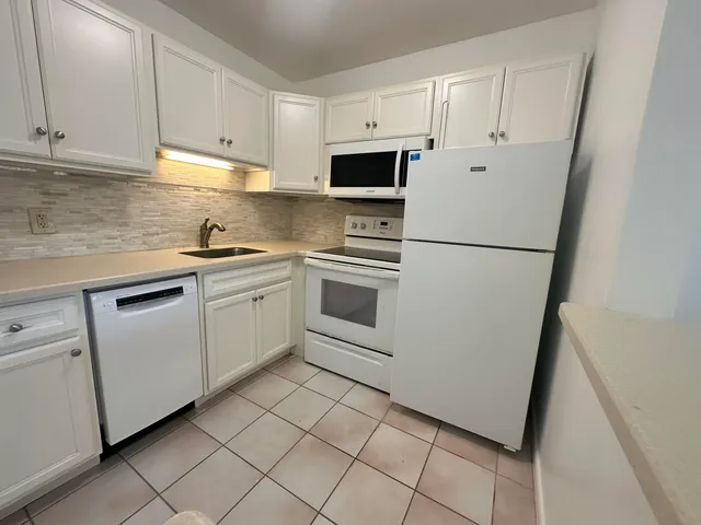 a kitchen with white cabinets and white appliances