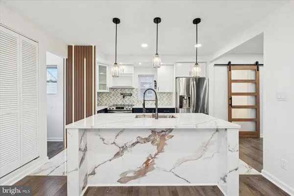 a view of kitchen with stainless steel appliances kitchen island granite countertop a refrigerator a sink and white cabinets