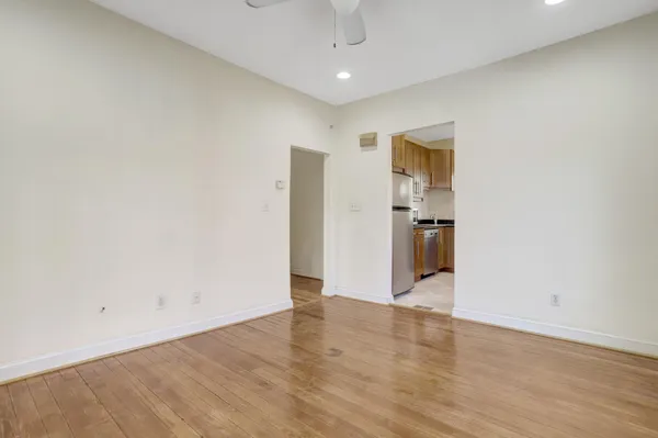a view of an empty room with wooden floor and a window