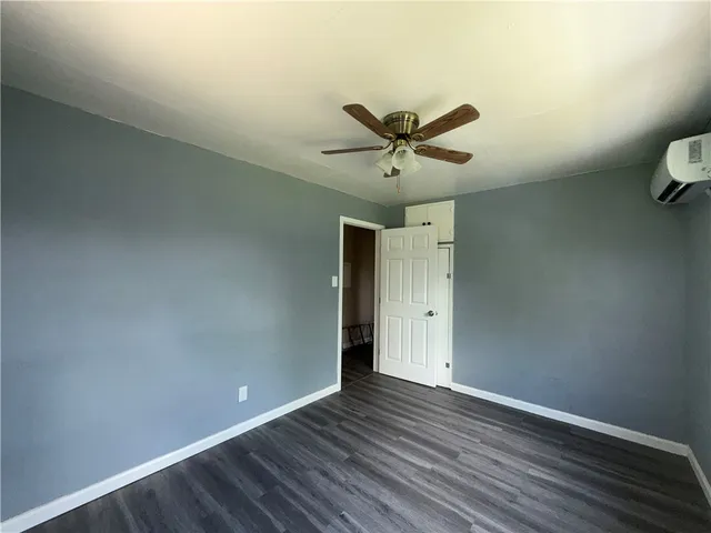 an empty room with wooden floor and a ceiling fan