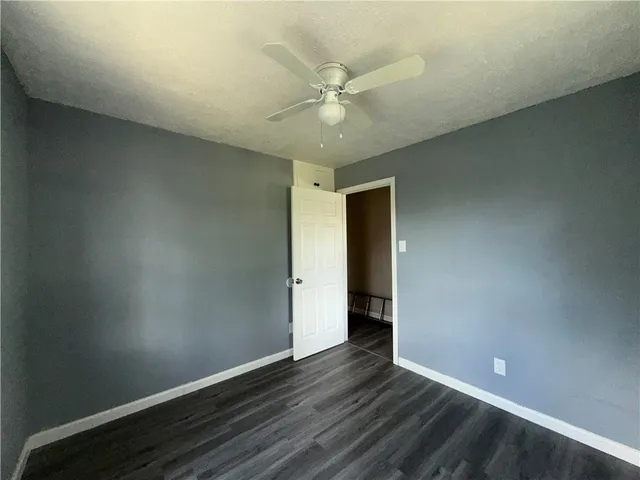 an empty room with wooden floor and fan