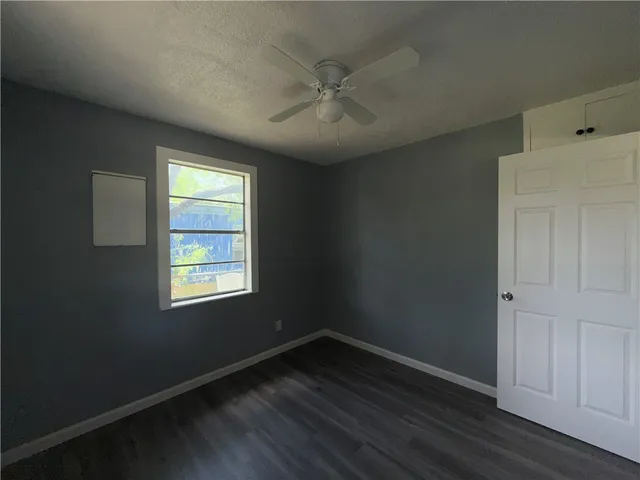 an empty room with wooden floor closet and windows